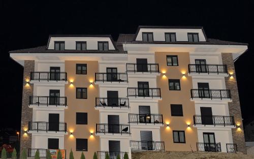- un grand bâtiment blanc avec balcon la nuit dans l'établissement NIDEHO Estate Apartmani, à Zlatibor