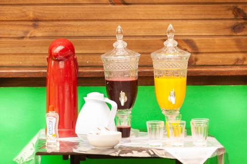a table with three glass containers of different colored liquids at Recanto do Sossego in Garopaba