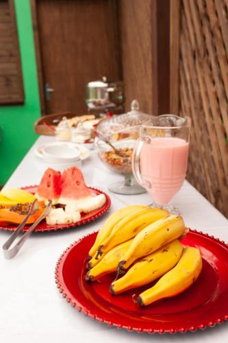 a table with two plates of bananas and a pink drink at Recanto do Sossego in Garopaba