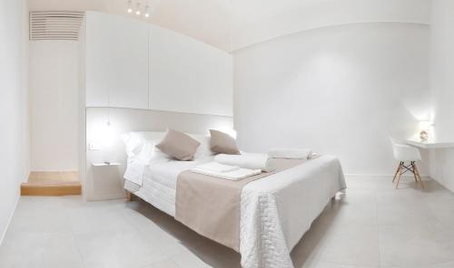 a white bedroom with a bed and a table at Cattolica Apartments in Cattolica