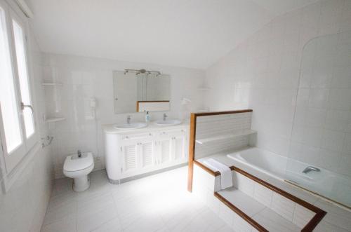 a white bathroom with a toilet and a sink and a tub at Villa Serpentona in Cala Galdana