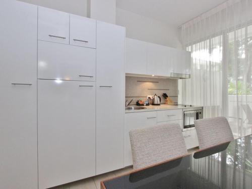a white kitchen with a table and two chairs at PalmCove DriftAway in Palm Cove