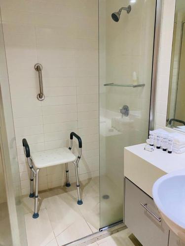 a bathroom with a shower and a chair in it at PalmCove DriftAway in Palm Cove