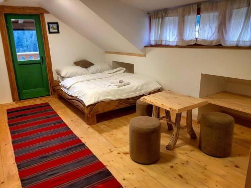 a bedroom with a bed and a table and a green door at Apartman Jahorina Dolina mira in Pale