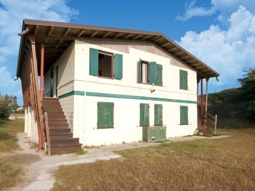 une petite maison blanche avec volets verts dans l'établissement Belvilla by OYO Brezza di mare, à Rosolina Mare