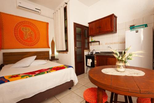 a bedroom with a bed and a table and a kitchen at Recanto do Sossego in Garopaba