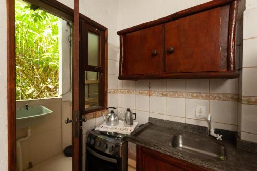 a kitchen with a sink and a stove and a window at Recanto do Sossego in Garopaba