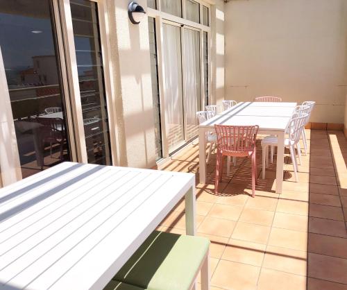 a balcony with white tables and chairs on a balcony at Seaspray Villa 5 in Shoal Bay