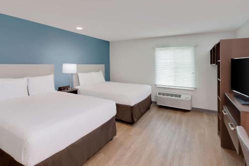 a hotel room with two beds and a flat screen tv at WoodSpring Suites Bakersfield East in Bakersfield
