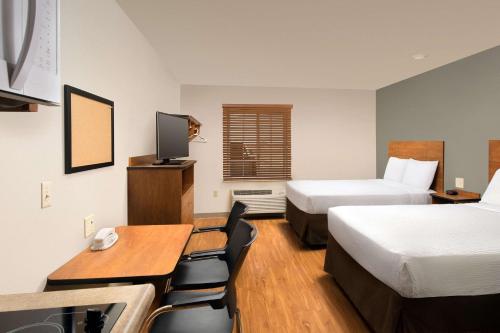 Habitación de hotel con 2 camas, mesa y sillas en WoodSpring Suites Hobbs en Air Base City
