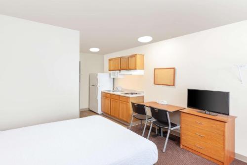 a hotel room with a bed and a desk and a kitchen at WoodSpring Suites Sioux Falls in Sioux Falls
