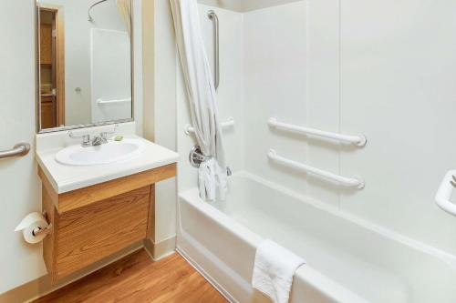 a white bathroom with a sink and a shower at WoodSpring Suites Raleigh Apex in Apex