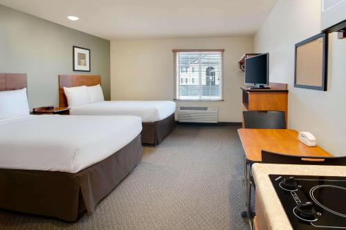 a hotel room with two beds and a kitchen at WoodSpring Suites Columbus North I-270 in Columbus