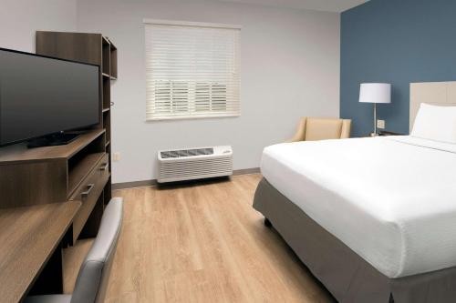 a bedroom with a bed and a flat screen tv at WoodSpring Suites Miami Southwest in Kendall