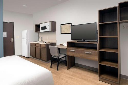 a room with a desk with a television and a kitchen at WoodSpring Suites Miami Southwest in Kendall