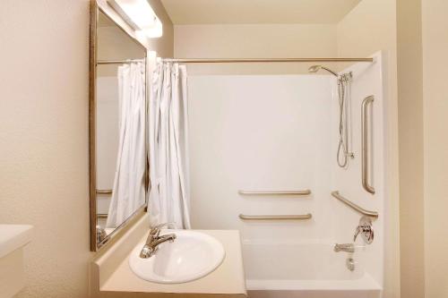 a white bathroom with a sink and a shower at WoodSpring Suites Lake Charles in Lake Charles