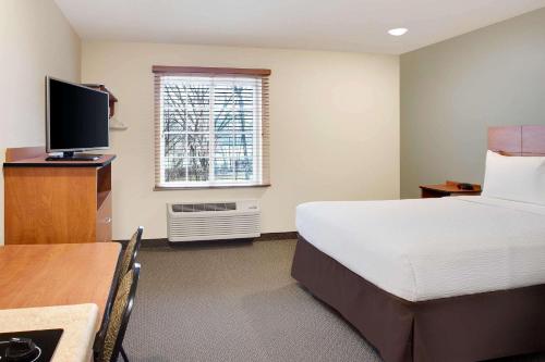 a hotel room with a bed and a table and a television at WoodSpring Suites Virginia Beach in Virginia Beach