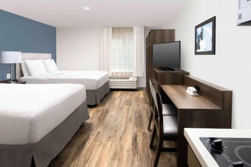 a hotel room with two beds and a television at WoodSpring Suites Austin South Central I-35 in Austin