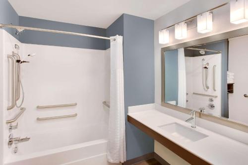 La salle de bains est pourvue d'une baignoire, d'un lavabo et d'un miroir. dans l'établissement WoodSpring Suites Nashville near Rivergate, à Goodlettsville