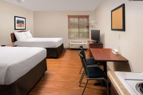 a hotel room with two beds and a desk at WoodSpring Suites Memphis Southeast in Memphis