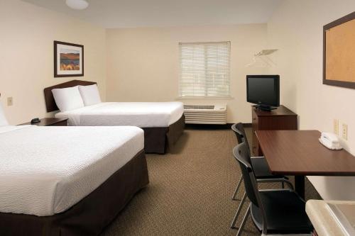 a hotel room with two beds and a desk at WoodSpring Suites San Antonio Fort Sam in San Antonio