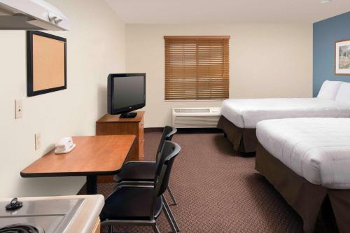 Habitación de hotel con 2 camas, escritorio y TV. en WoodSpring Suites San Antonio North Live Oak I-35 en San Antonio