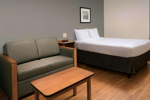 a hotel room with a bed and a couch and a chair at WoodSpring Suites Odessa in Odessa