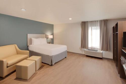 WoodSpring Suites Houston Northwest في هيوستن: غرفه فندقيه بسرير وكرسي