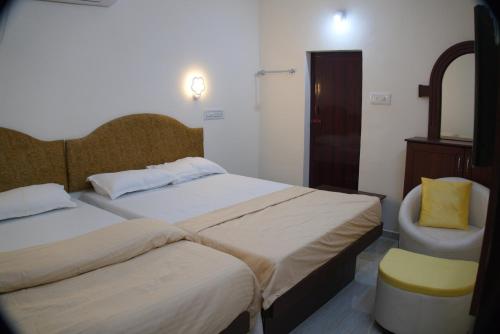 a hotel room with two beds and a chair at Hotel Sunrise in Kanyakumari