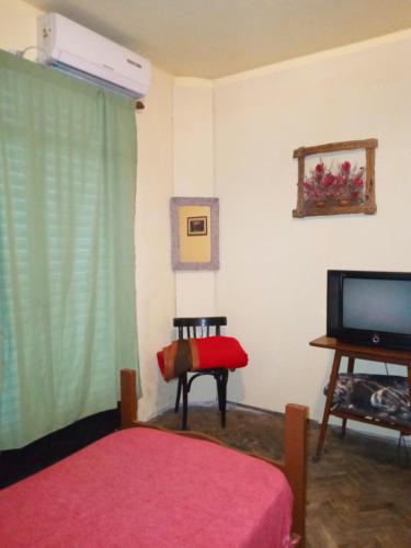 a bedroom with a bed and a television and a table at Hostel en rosario in Rosario