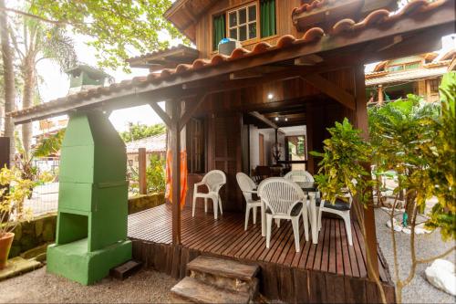 a house with a wooden deck with a table and chairs at Recanto do Sossego in Garopaba