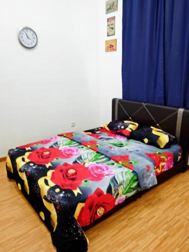 a bed with a colorful blanket on the floor with a clock at Homes Asrafiq - Homestay Merlimau Serkam Melaka in Merlimau