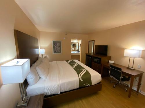 a hotel room with a bed and a desk with a computer at Quality Inn in Pulaski