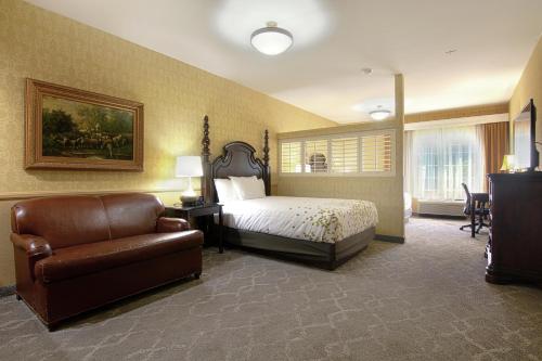 a bedroom with a bed and a chair and a couch at Azure Hotel&Suites Ontario Trademark Collection by Wyndham in Ontario