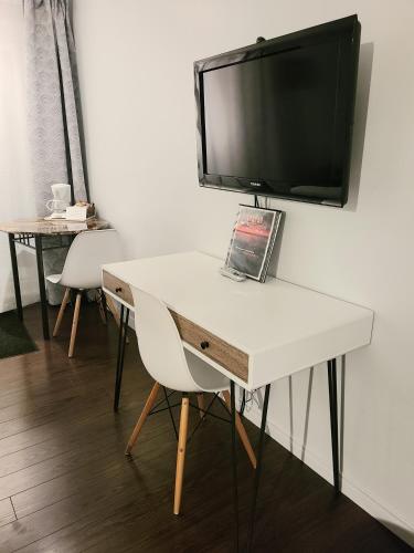 a white desk with a television on a wall at Horizon 777 in Saint-Siméon