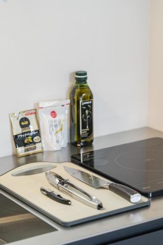 a cutting board with knives and a bottle of oil at Okinawa Villa KILOHANA in Inbu