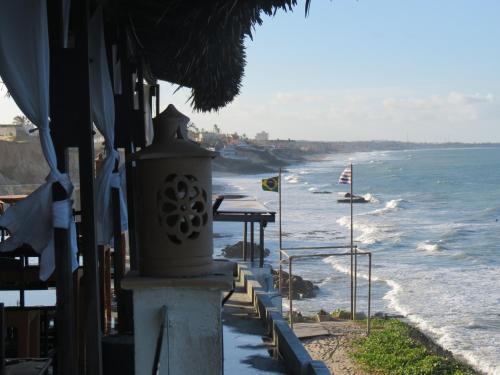 a building next to a beach with the ocean at La Suite Praia Hotel in Caucaia