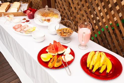 a white table with two plates of fruit and a drink at Recanto do Sossego in Garopaba
