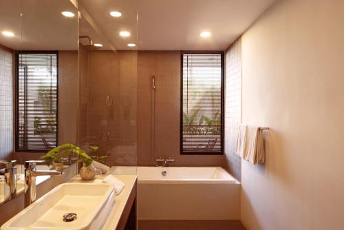 a bathroom with a tub and a sink and a shower at Penh House Hotel in Phnom Penh