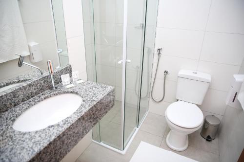 a bathroom with a toilet and a sink and a shower at Raf Hotel in Umuarama