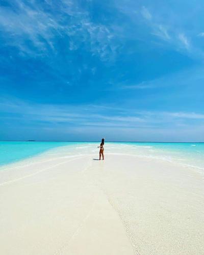 a person walking on a beach in the ocean at Veli Beach Inn in Mathiveri