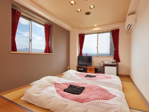 a bedroom with a bed in a room with windows at Hatago Hashimoto in Ozu