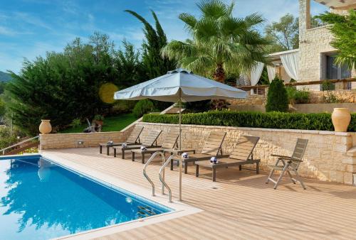 a patio with chairs and an umbrella next to a pool at Ionian Diamond Villas in Mikros Gialos