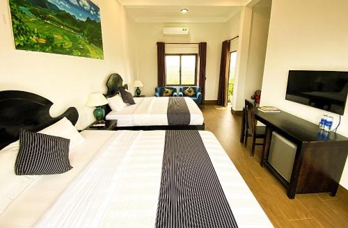 a hotel room with two beds and a flat screen tv at Karst Villas Phong Nha in Phong Nha