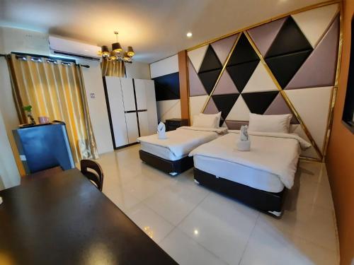 a hotel room with two beds and a table at Debua Mahasarakham in Maha Sarakham
