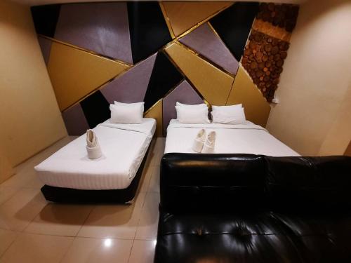 a room with two beds and a leather couch at Debua Mahasarakham in Maha Sarakham