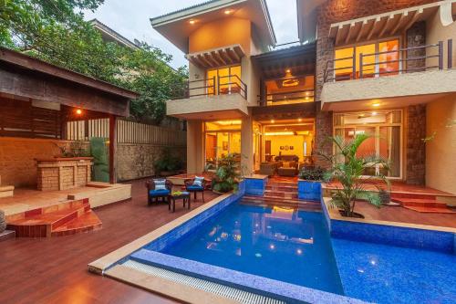 a house with a swimming pool in front of it at StayVista's The Happy Hive - Cozy rooms and a pool for a delightful stay in Lonavala