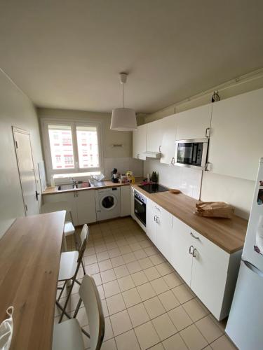 une cuisine avec des armoires blanches et une table et des chaises dans l'établissement Chambre calme (Neptune)-Proche Gare & Hyper centre, au Mans