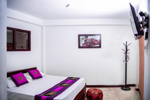 a bedroom with a bed with pink pillows and a tv at D Family Resort in Anuradhapura
