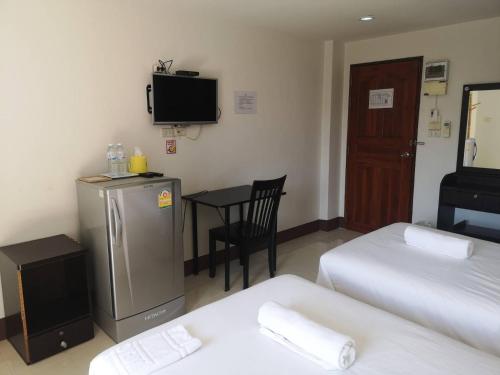 a room with two beds and a television and a table at Ing Loei Place in Loei